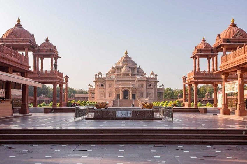 A large, ornate building with domes and arches, surrounded by a paved area with a fountain. 1
