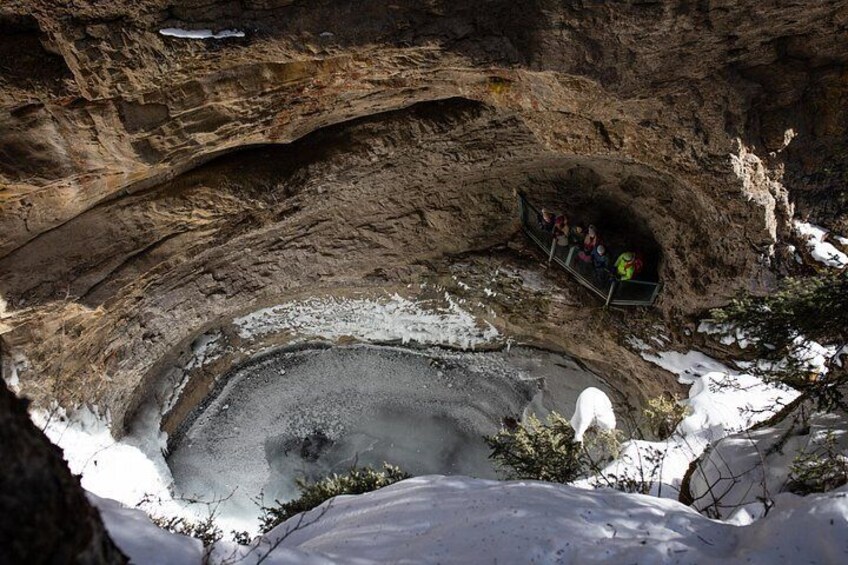 A snow-covered landscape with a large cave opening, a group of people inside the cave, and a snow-covered ground. 4