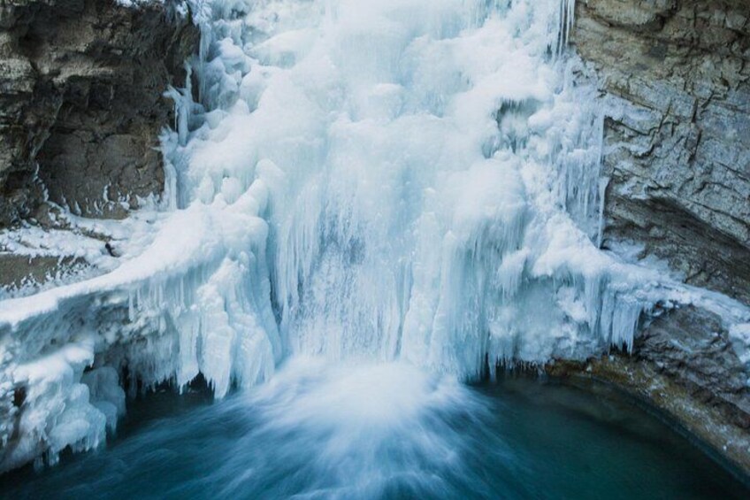 A frozen waterfall cascading down a rocky cliff. 2