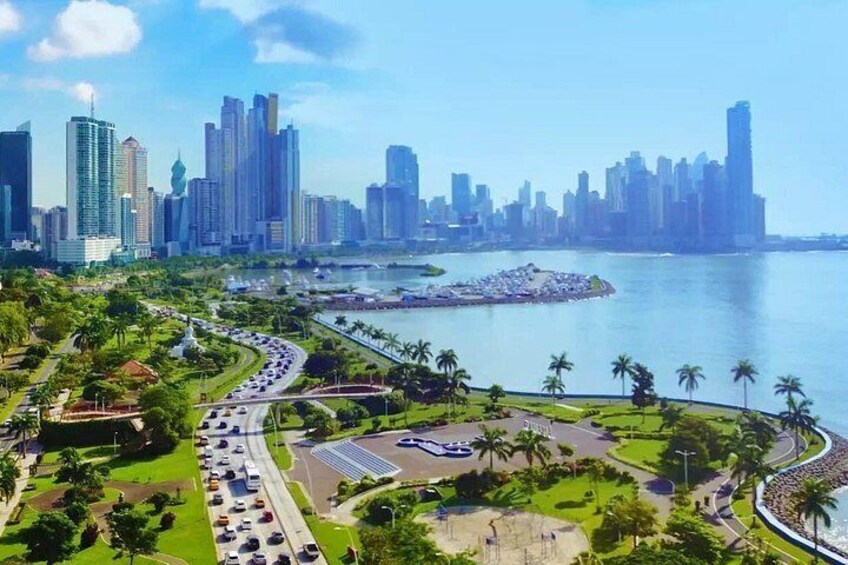 Un horizonte urbano con rascacielos, un paseo marítimo y una transitada vía con vehículos. 1