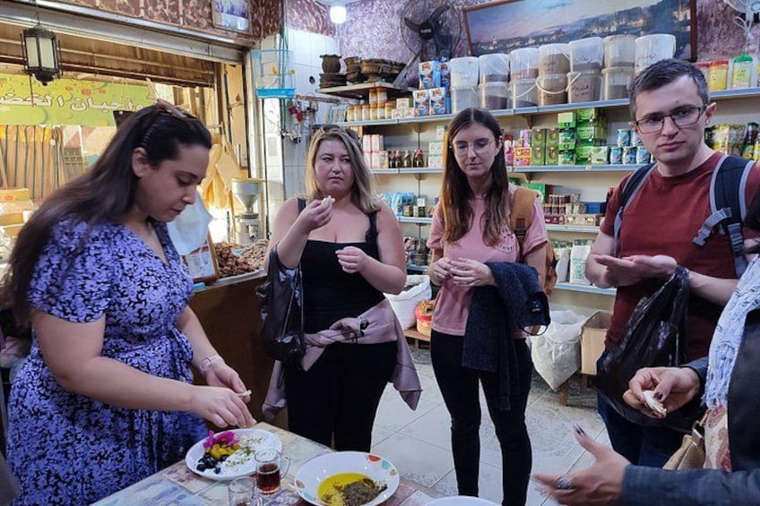 A group of people at a market stall with various food items and drinks. 1