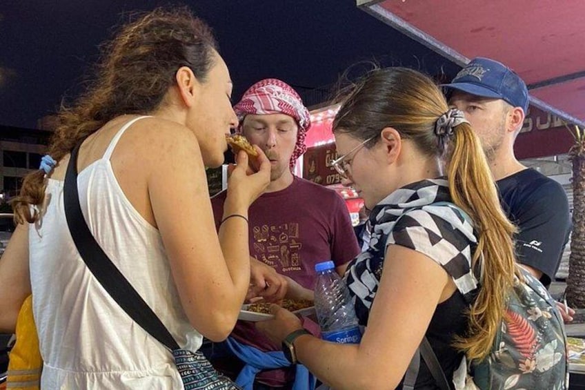 People eating at an outdoor food stall. 2