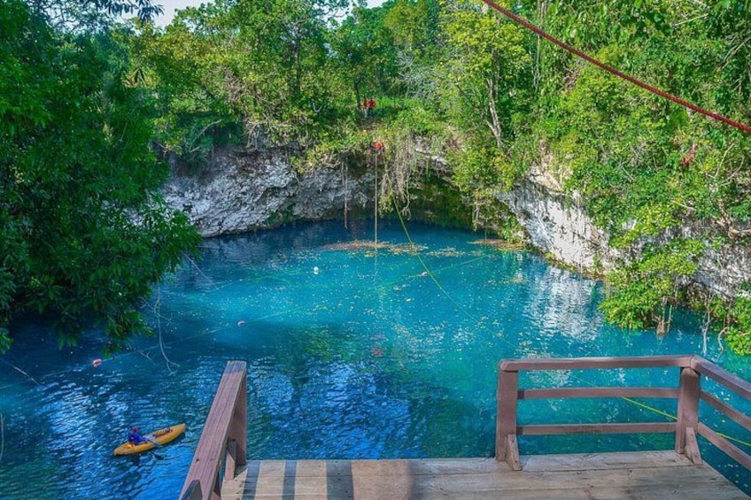 Un muelle de madera que se adentra en una piscina azul cristalina rodeada de exuberante vegetación. 3