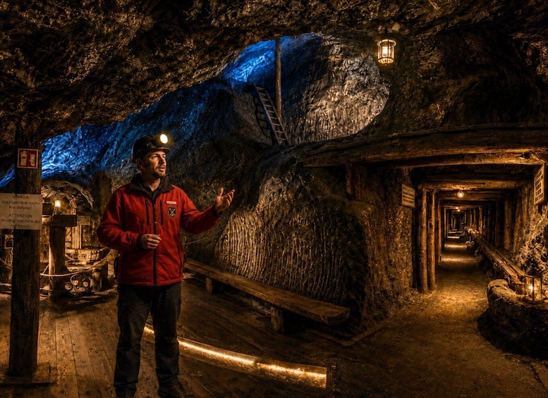 A person in a red jacket standing in a dimly lit tunnel with wooden structures and a blue-lit wall. 3