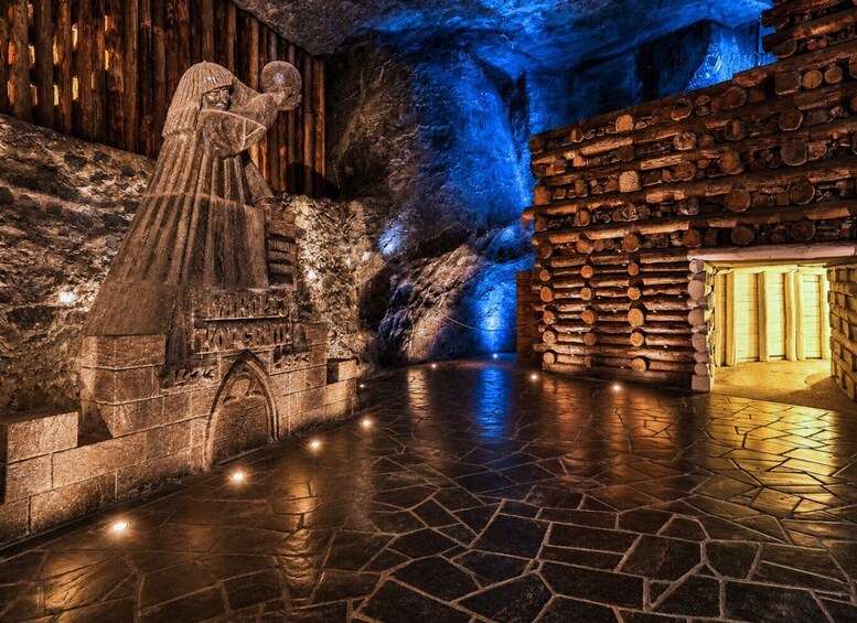 Una statua in pietra, un muro di legno e una grotta illuminata di blu. 5