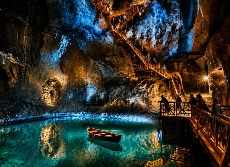 A cave with a wooden boat on water, wooden walkways, and people observing. 1