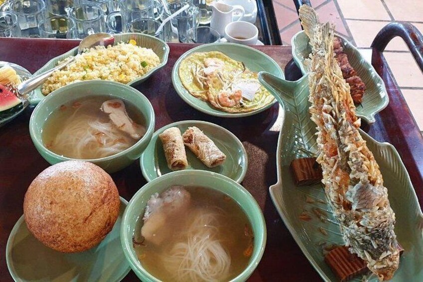 A table with various dishes including soup, rice, and a whole fish. 2