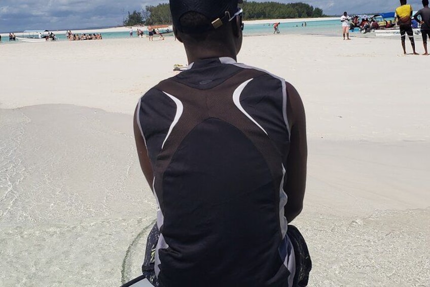 A person sitting on a beach with a clear sky and distant trees. 2