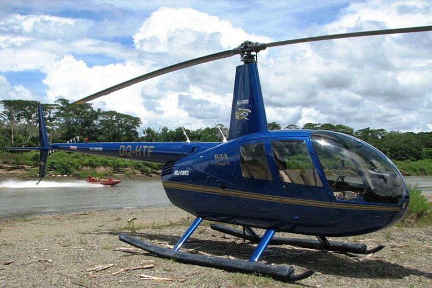 Ein blauer Helikopter mit der Kennung 09-KTF steht auf einer unbefestigten Fläche in der Nähe von Wasser. 3