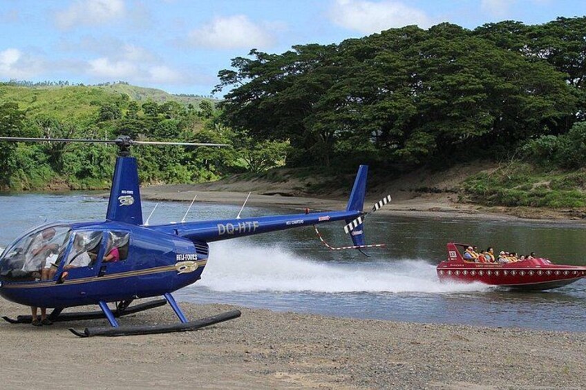 Ein blauer Hubschrauber auf einer Landefläche, ein rotes Boot, das eine Bugwelle hinterlässt, und ein Fluss mit Grün im Hintergrund. 2