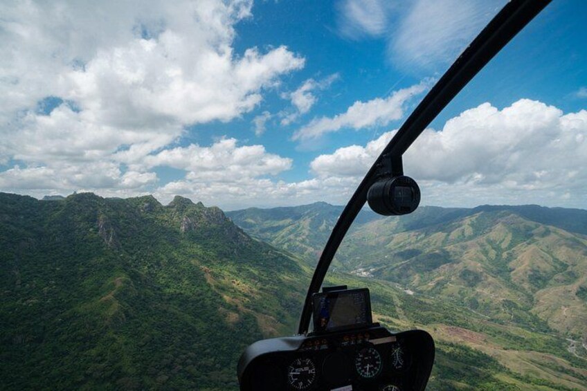 En helikoptercockpit med utsikt över ett bergigt landskap. 2
