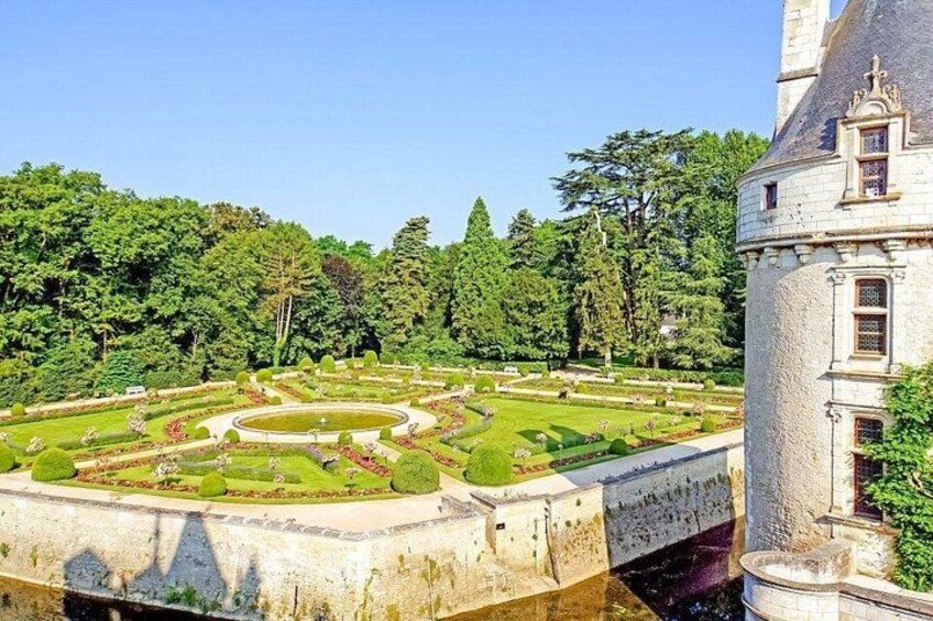 Un jardín ajardinado con una fuente circular central, rodeado de céspedes cuidados y árboles. 5