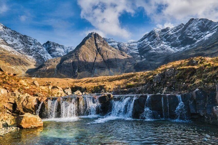 A mountainous landscape with a waterfall cascading into a pool, surrounded by snow-capped peaks. 2