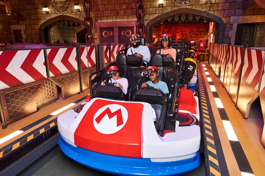 A ride with a red and white design, passengers wearing safety helmets, and a brick wall background. 5