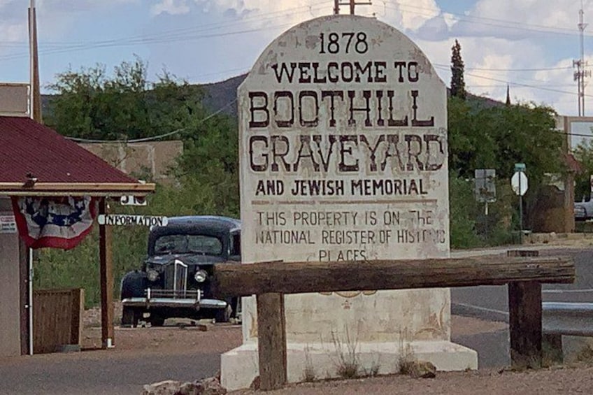 Ein historisches Schild für den Boothill Friedhof und das jüdische Denkmal, errichtet 1878, mit einer klassischen amerikanischen Flagge und einem Oldtimer im Hintergrund. 4