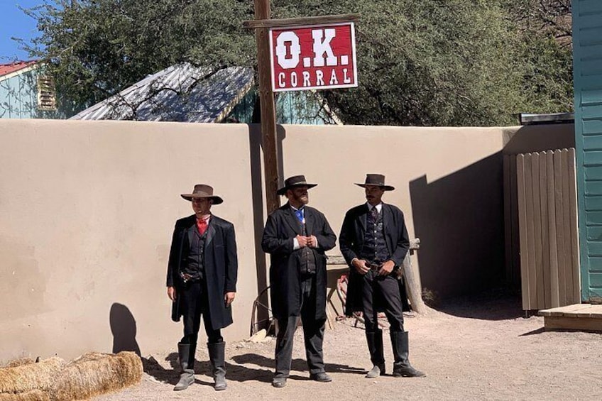 Three men in suits and hats standing in front of a sign that reads 'O.K. CORRAL.' 4
