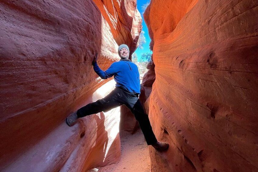 Una persona escalando un cañón estrecho con paredes de roca roja. 3
