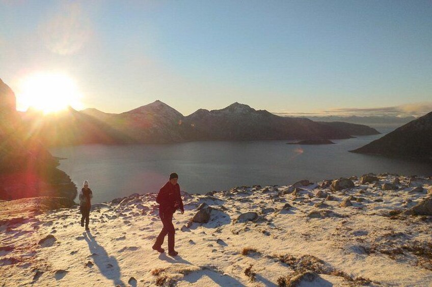 Un paysage montagneux avec un lac et deux personnes qui marchent sur un sentier enneigé. 1