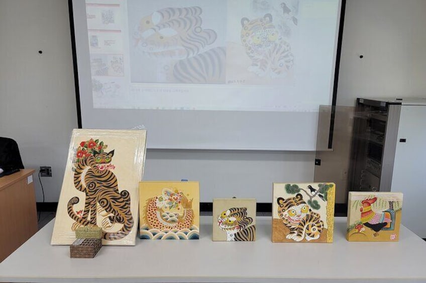 A display of various animal-themed artworks on a table in front of a projector screen. 2