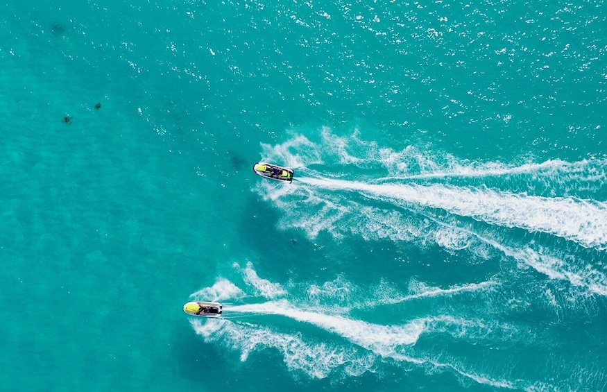 Two jet skis creating wakes in turquoise water. 3