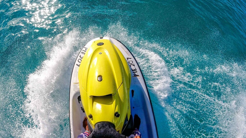 A yellow jet ski moving through turquoise water. 5