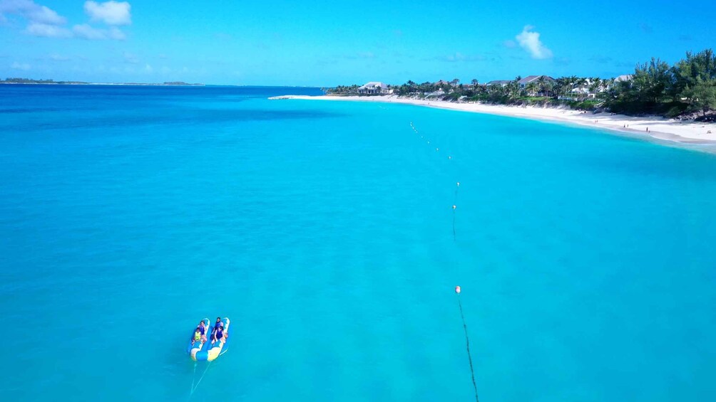 A clear blue sea with a beach, a boat, and a distant shoreline with buildings. 4