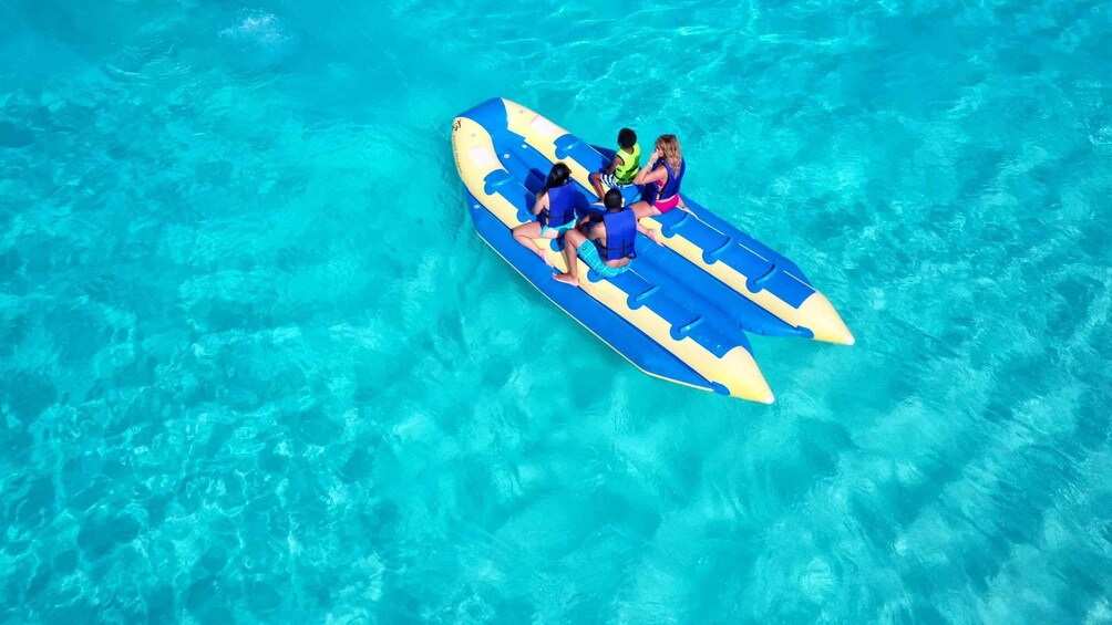 A group of people on a blue and yellow raft in clear turquoise water. 2