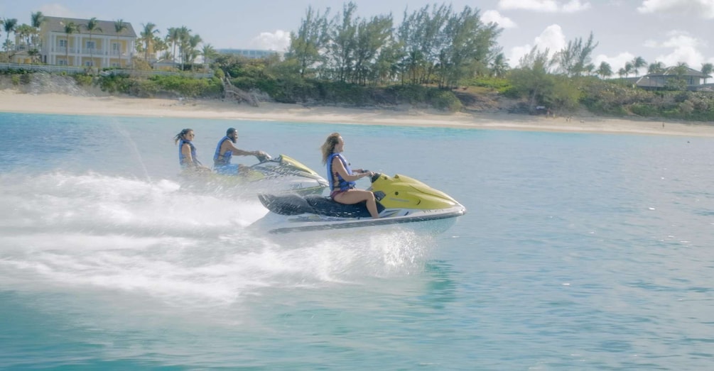 A person jet-skiing on turquoise water with a beach and palm trees in the background. 5