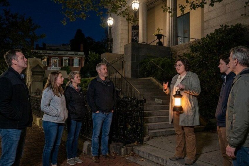 A group of people standing on a staircase at night, with a person holding a lantern. 2