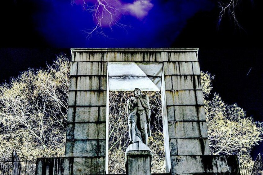 A statue of a man in a coat and hat, standing in front of a stone archway with a lightning bolt in the background. 5