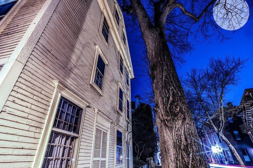 A large tree in front of a building with multiple windows and a moon in the sky. 2