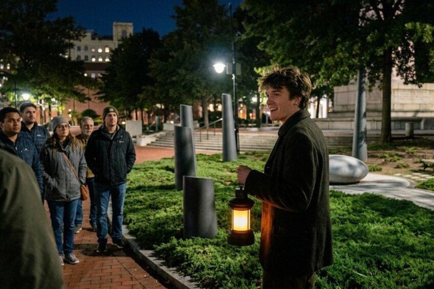 A person holding a lantern in a park at night. 1