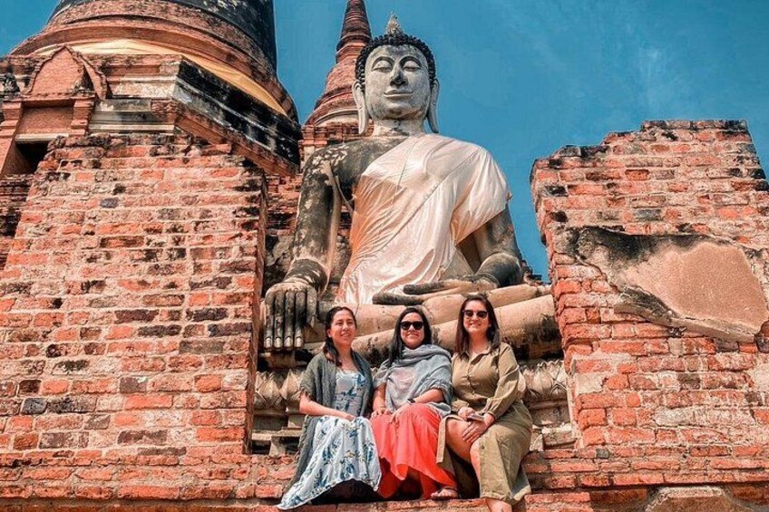 A large Buddha statue, brick walls, and a clear blue sky. 4