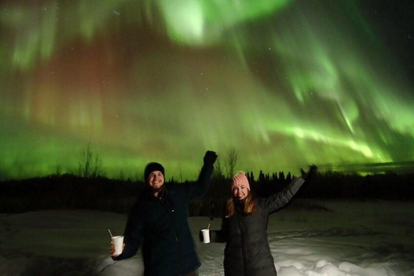 Two people standing on ice with a green aurora in the background. 5