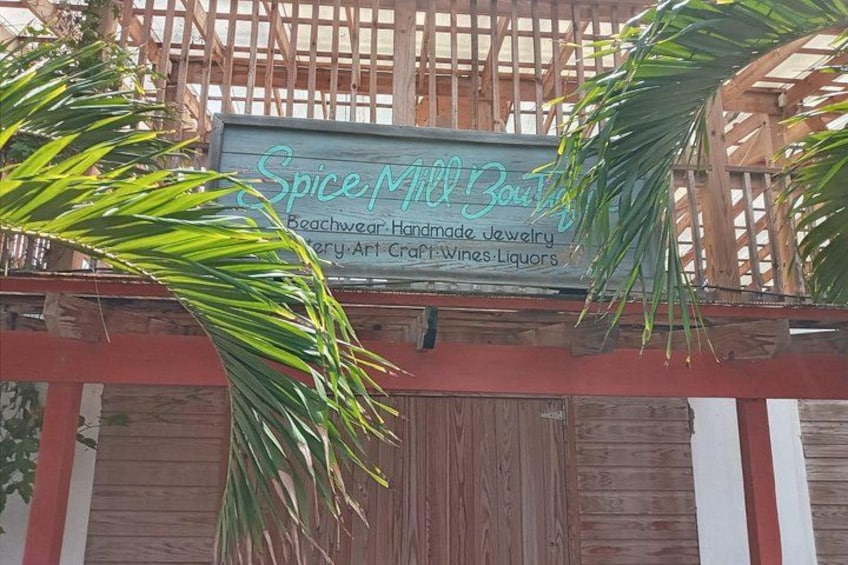 A wooden structure with a sign for Spice Mill Boutique, listing offerings like beachwear, handmade jewelry, and more. 2