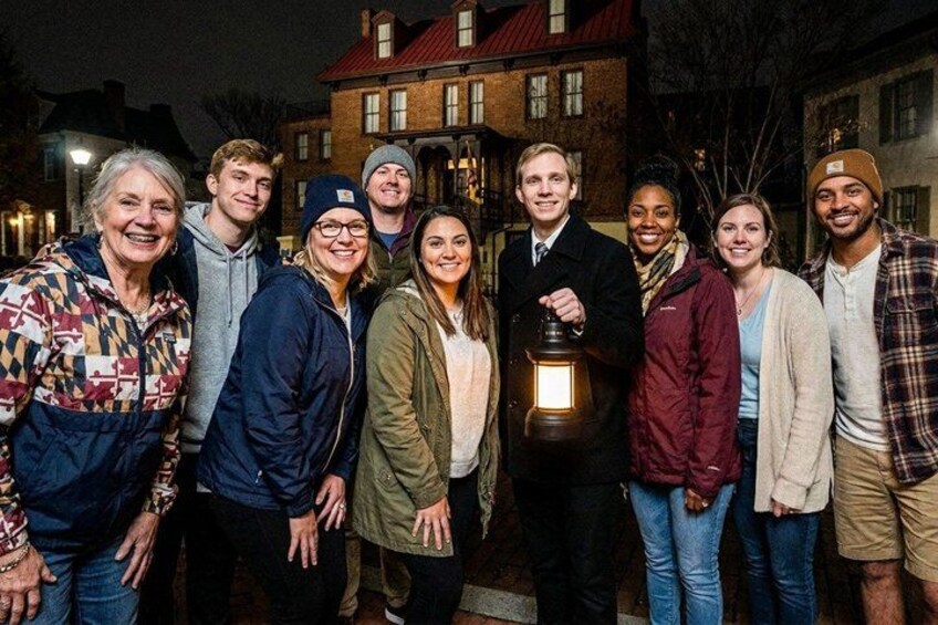 A group of people standing outdoors at night with a building in the background. 3
