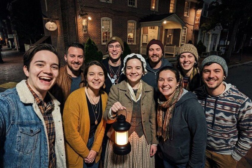 A group of people standing in front of a brick building at night. 2