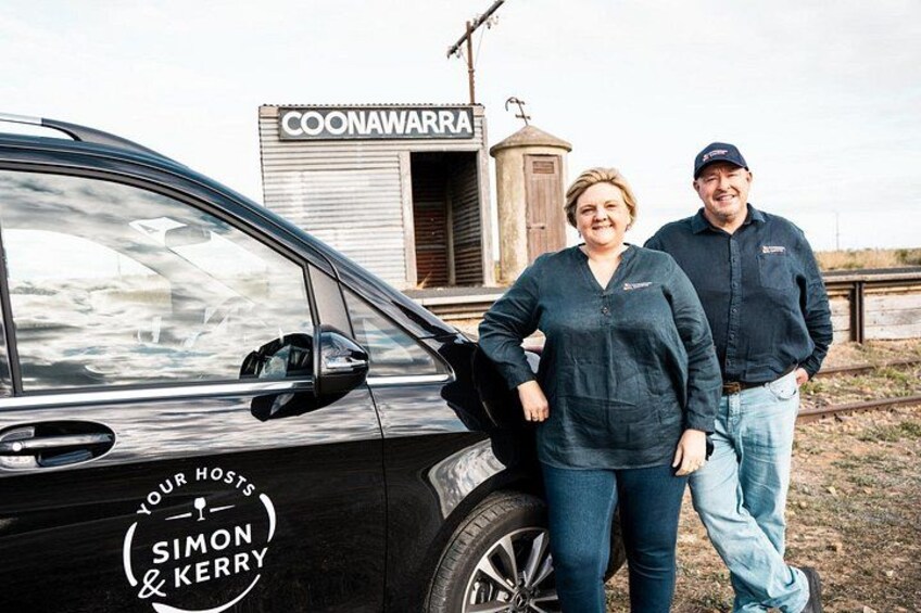 A black car parked in front of a building with a Coona Waterra sign. 3