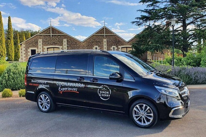 A black van parked in front of a building with a sign that reads 'COONAWARRA Experiences.' 2