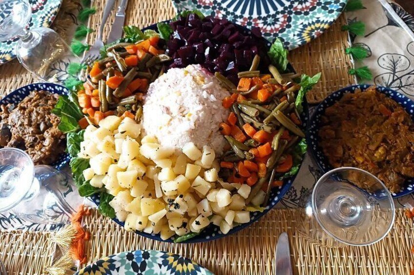 A table with a variety of dishes including rice, vegetables, and a meat dish, with glasses of water and a patterned tablecloth. 4
