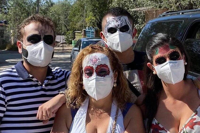 Un grupo de personas con mascarillas posando frente a un vehículo. 2
