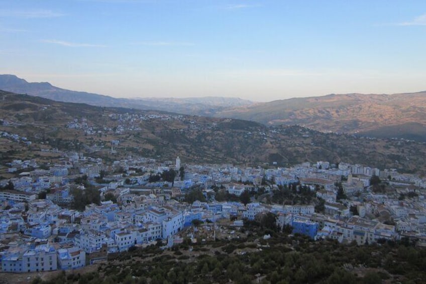 A town with white buildings, a prominent church, and rolling hills in the background. 2