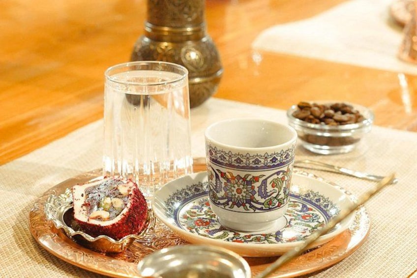 Una mesa con un plato de comida, una taza, un vaso y un cuenco de granos de café. 2