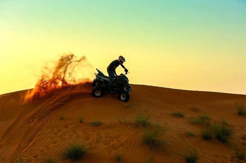 A person riding an ATV on a sand dune. 1