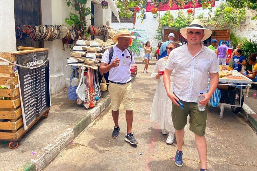 Un marché de rue où l’on voit un homme en chemise et chapeau blancs, un autre homme en chemise bleue et une femme en robe blanche. 4