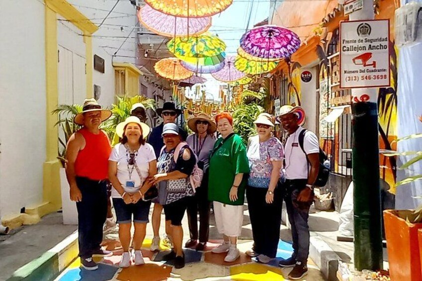 Un groupe de personnes se tient dans une rue, des parapluies colorés les protégeant du soleil ou de la pluie. 2