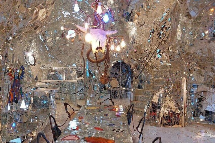 A room with a chandelier, mirrors, and abstract art. 2