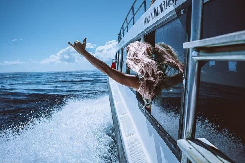 A person leaning out of a boat window, water splashing around, with a clear sky and calm sea in the background. 3