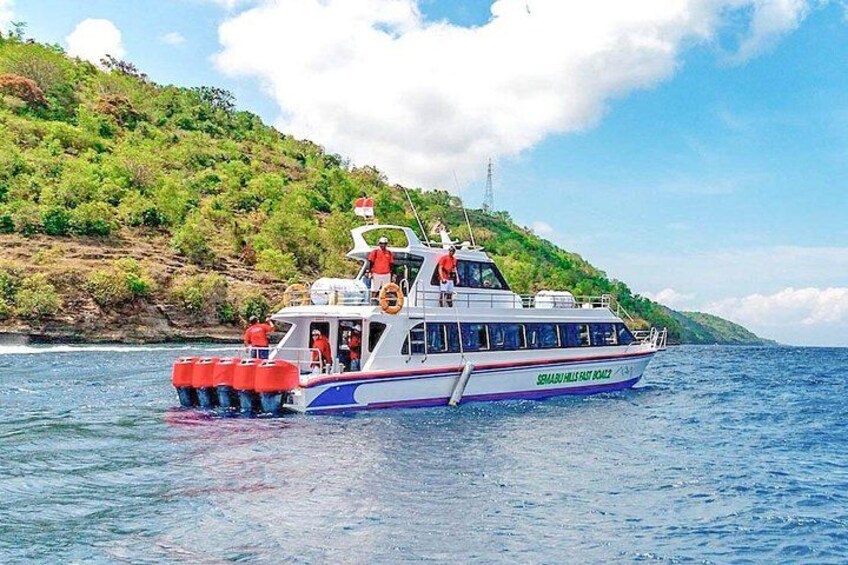 A boat named 'Saba Hills Fast Boat' on a body of water with a green, hilly landscape in the background. 1