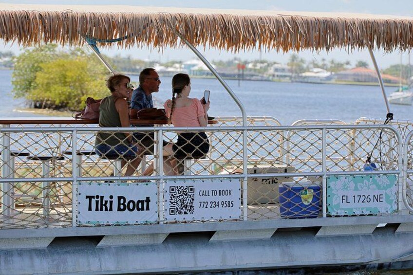 Un bote con techo de paja, pasajeros y un cartel que dice 'Tiki Boat'. 4